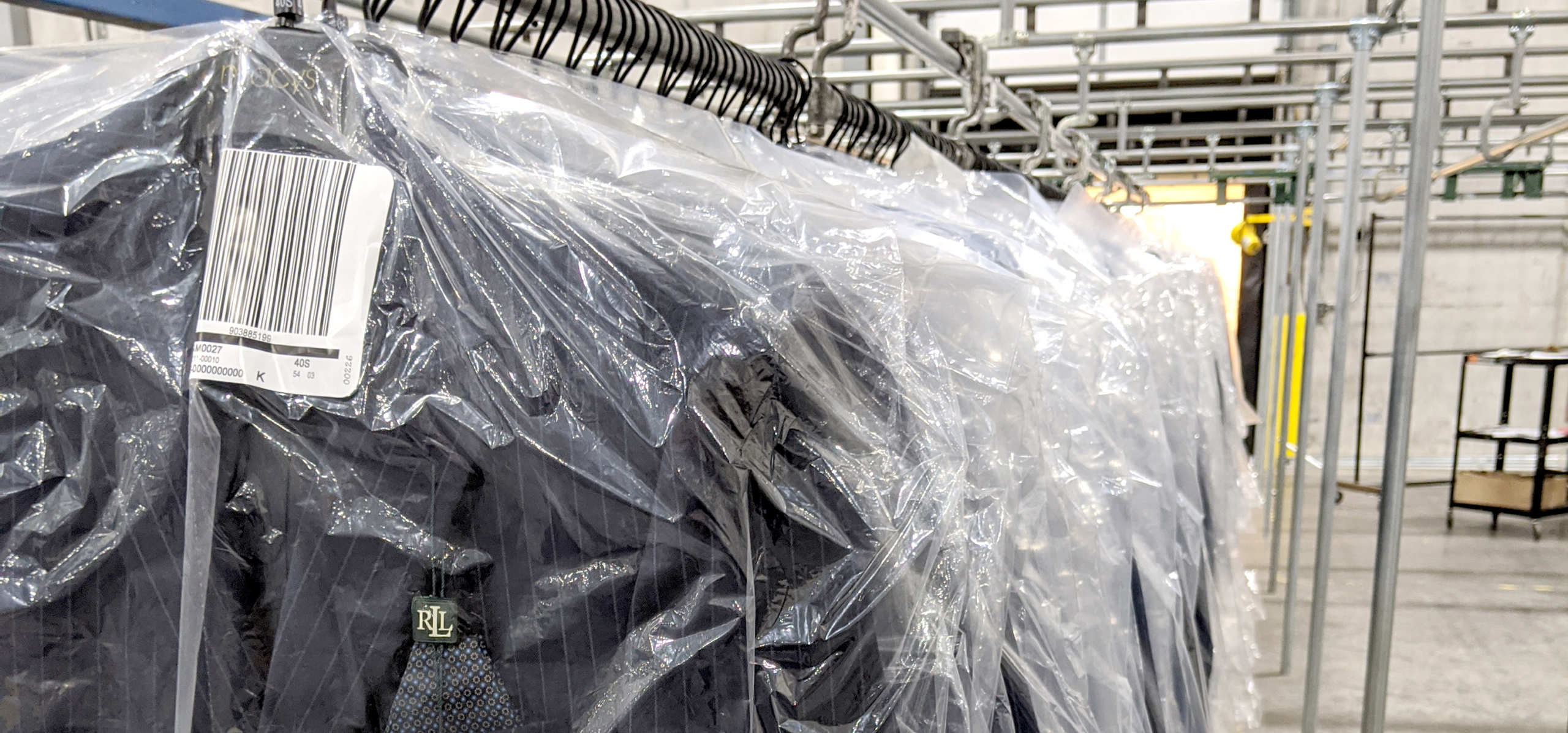 Close-up of polybagged suits on GOH speed rail with barcode ticketing at UDS